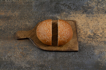 Wall Mural - Half cut tasty bun with sesame seeds on wooden board