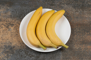 Three ripe bananas on white plate