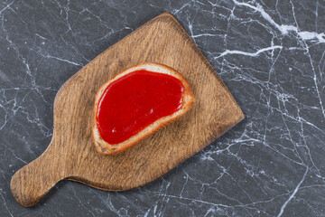 Wall Mural - Toothsome strawberry jam on bread on the board , on the marble background