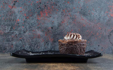 Wall Mural - A dark plate of a chocolate cake with cocoa powder