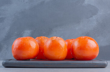 Wall Mural - Close up photo of Ripe orange persimmon fruit . On wooden board.