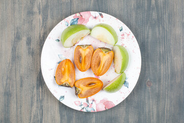 Wall Mural - Sliced delicious persimmon with sliced green apple