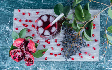 Wall Mural - a sliced of pomegranate and juice on the board , on the blue background