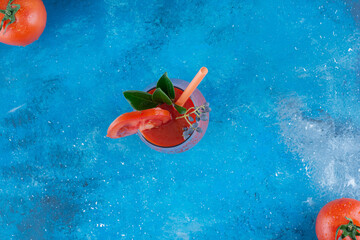 Wall Mural - Ripe tomato and tomato juice on the board, on the blue background