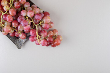 Wall Mural - Clusters of grape and an ornate tray on marble background