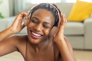 Wall Mural - Enjoying favorite playlist during home workout. Happy black woman wearing wireless headphones and listening to music