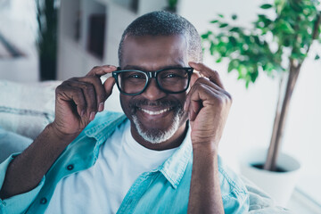 Portrait of positive aged man sit in modern house living room try enjoy new specs optics special offer