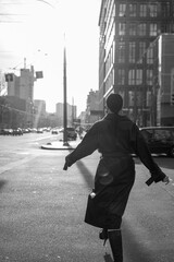 Wall Mural - Girl on the street in a black coat. Stylish girl in a black raincoat on the background of a high glass house