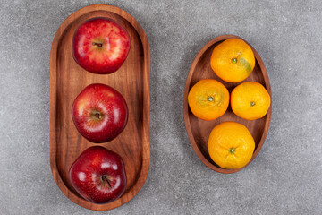 Wall Mural - Red apples with sweet tangerines on a wooden board