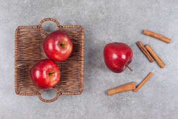 Two red apples in wooden basket with cinnamon sticks