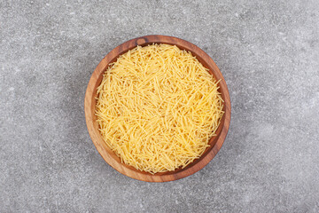 Wall Mural - Bunch of uncooked pasta in wooden bowl