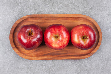 Wall Mural - Three red apples on wooden plate