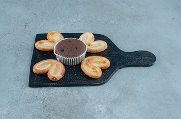 Flaky cookies and a cupcake on a black board on marble background