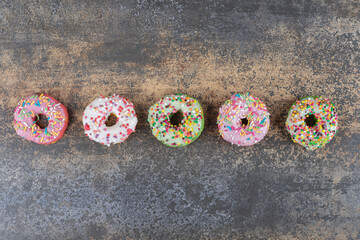 Wall Mural - Five donuts lined in a row on wooden background