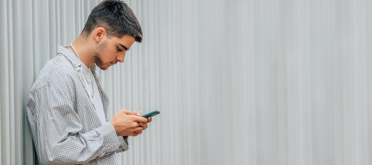 Wall Mural - young man on the street looking at the mobile phone