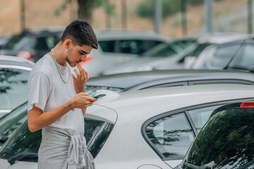 young man with mobile phone looking at cars