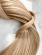A strand of blond hair on a white background. Close-up.