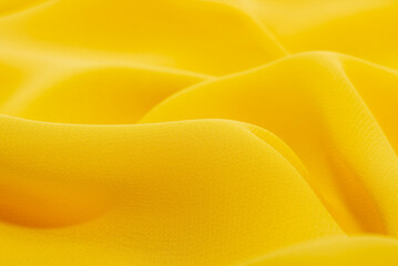 Texture of crumpled yellow fabric. Background of luxury textile or material in bright yellow color