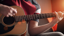 Young Man Learning To Play Acoustic Guitar Online At Home. Close-up.