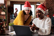 © DC Studio - Diverse women working in team at startup job with festive decorations and christmas tree, people wearing santa hat at company workplace. Seasonal holiday ornaments and lights during winter.