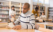 © JackF - Young adult man working with books, finding information at library