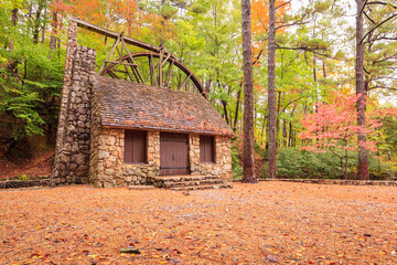 Wall Mural - Stone building with chimney and mill wheel in forest during autumn