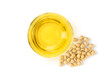 Glass bowl of soybean oil with soybeans isolated on white background. Top view
