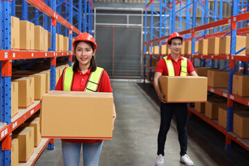 Group of warehouse workers man and woman with hardhats and reflective jackets carrying a large box for delivery to production stock and inventory in retail warehouse logistics, distribution center