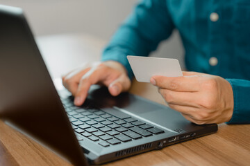 Poster - Man uses a laptop to register through a credit card to make online purchases. Credit card safe online shopping and payment concept.