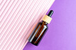 Amber glass cosmetic dropper bottle with blank label on double pink and purple background. Trendy beauty product design, branding. Mockup cosmetics