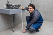 © Vitaliy - Handsome cheerful plumber measuring the length of sink in the bathroom