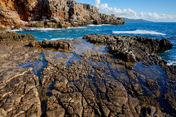 Top view azure blue sea with waves beating on beach and rocks.