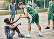 © C Coetzee/peopleimages.com - Basketball court, help or men holding hands in exercise wellness, competition workout or school training game. Teamwork support or sports diversity in match with black man or community student player