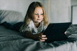 © F8  \ Suport Ukraine - Cute little girl use digital tablet while lying in bed