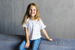 © F8  \ Suport Ukraine - Pretty happy little girl in casual wearing sitting on sofa