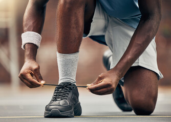 Fitness, running and shoes of black man for training for sports, motivation and start of workout. Exercise, health and wellness with runner fixing his laces in road for cardio, energy and performance