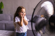 © F8  \ Suport Ukraine - Little girl enjoying air flow from fan at home. Summer heat