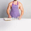 © oleg_ermak - Chef bodybuilder in protective apron and cook eggs on whie kitchen table. Muscular man cooking. Healthy food and dieting. Food additives for sportsman, daily calorie diet