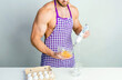 © oleg_ermak - Chef bodybuilder in protective apron uses a blender to beat scrambled eggs on whie kitchen table. Muscular man cooking.