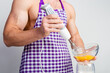 © oleg_ermak - Chef bodybuilder in protective apron uses a blender to beat scrambled eggs on whie kitchen table. Muscular man cooking.