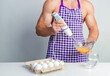 © oleg_ermak - Chef bodybuilder in protective apron uses a blender to beat scrambled eggs on whie kitchen table. Muscular man cooking.
