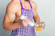 © oleg_ermak - Chef bodybuilder in protective apron uses a blender to beat scrambled eggs on whie kitchen table. Muscular man cooking.