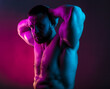 © oleg_ermak - Sportive man bodybuilder is posing in the colorful neon light with naked muscular torso showing chest, abdominal muscles in neon studio light.