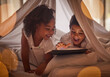 Children, tablet and night streaming online for movies, cartoon or educational games before bedtime in a blanket fort with a fun app. Excited boy and girl kid sharing, reading and internet addiction