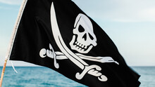 Black Pirate Flag With Skull Symbol On The Desert Island