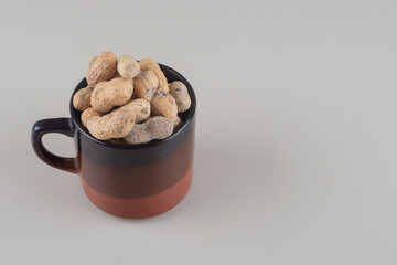 Pile of peanuts in a mug on marble background