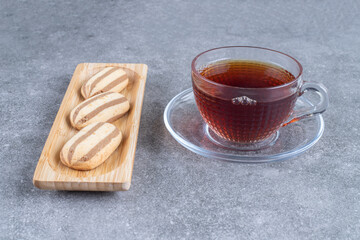 Oval shaped biscuits on wooden plate with cup of tea