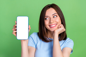 Wall Mural - Photo of positive pretty girl look hand hold empty space telephone display isolated on green color background