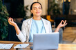 © Kateryna - Positive calm relaxing beautiful young mixed race woman, office worker, company manager, sitting at workplace in the office, resting from work, meditating with closed eyes, smiling