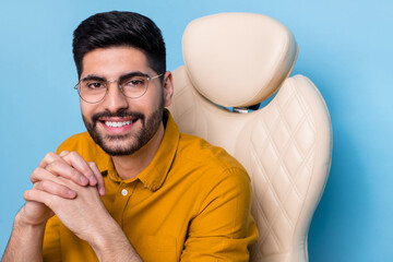 Wall Mural - Photo of cheerful intelligent person sit chair folded hands toothy smile isolated on blue color background